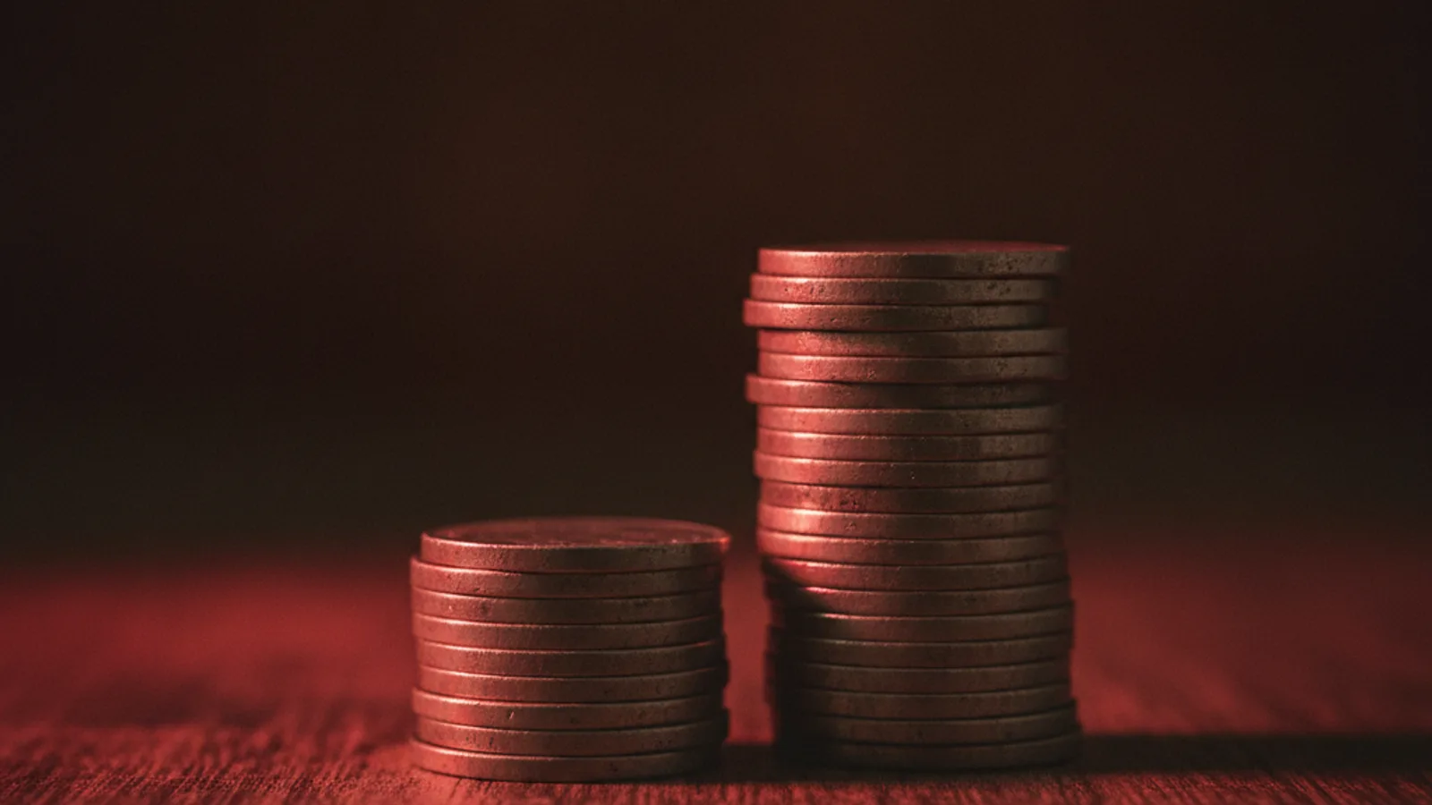 Duas pilhas de moedas de alturas bem diferentes sobre superfície escura