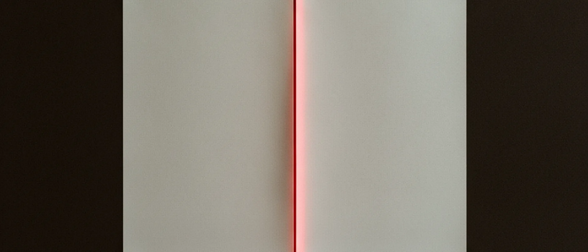 Duas folhas de papel off-white sobrepostas em mesa escura, separadas por uma linha de luz vermelha